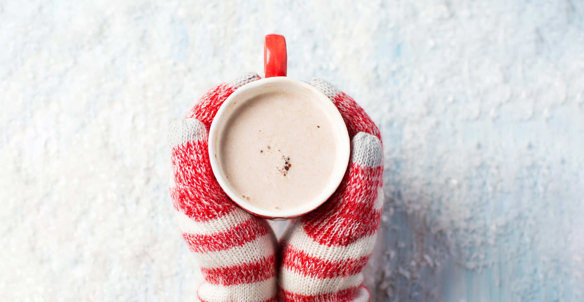 female hands in gloves holding hot chocolate over a snowy background