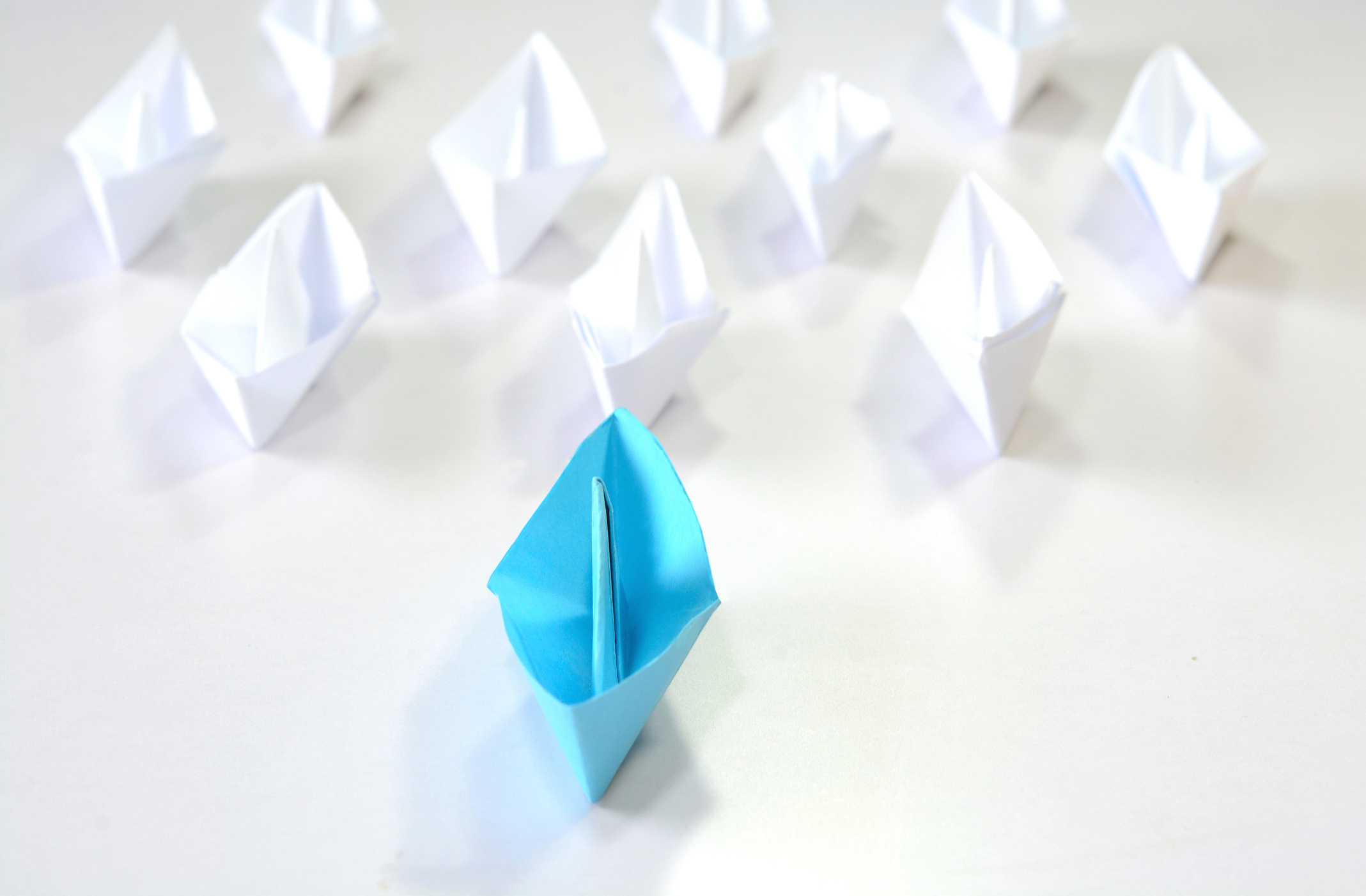 Leading from the front. Leadership concept of blue origami ship leading in the front.