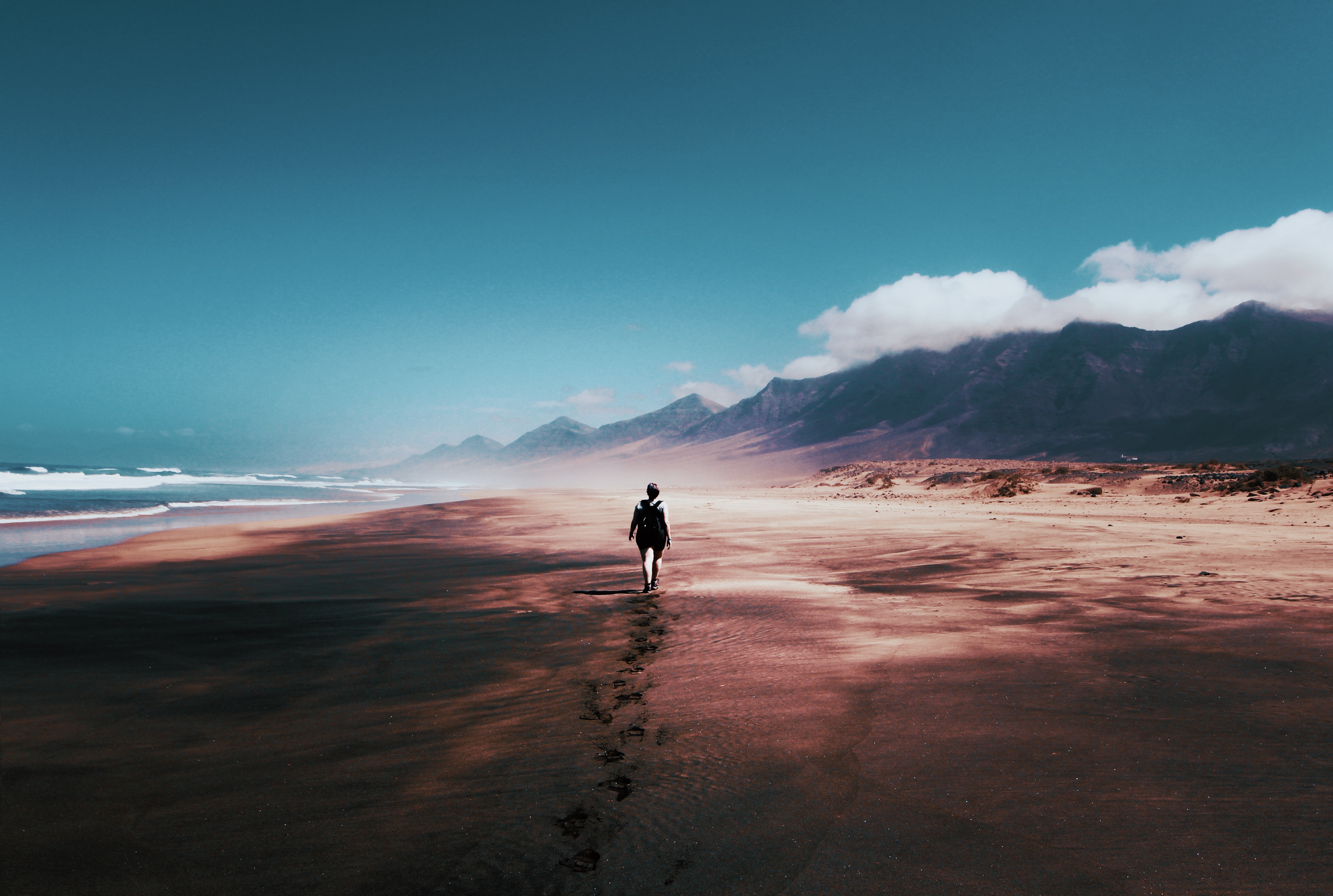 A person walks on a wide beach expanse