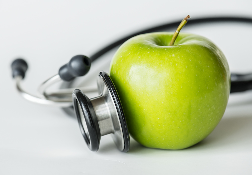 Closeup of an apple and a stethoscope healthy food and health concept