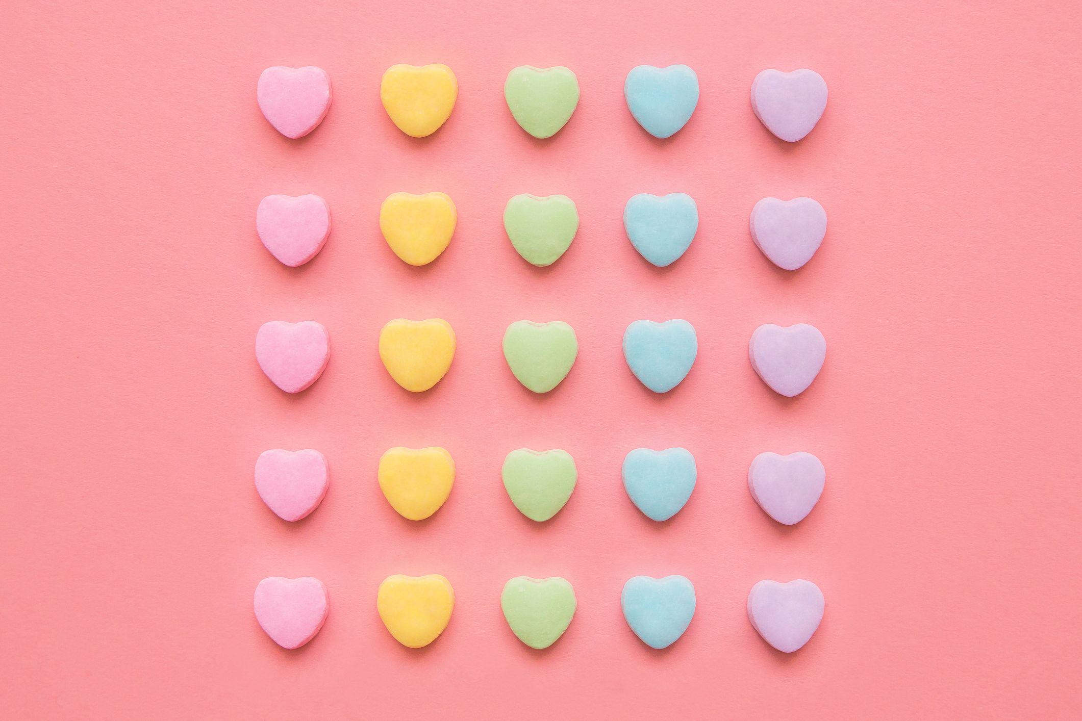 Love hearts background. Candy hearts on a pink background for Valentine&#039;s Day or anytime. Conceptual image to symbolism dating, marriage and/or equality, gay pride, or OCD and order.