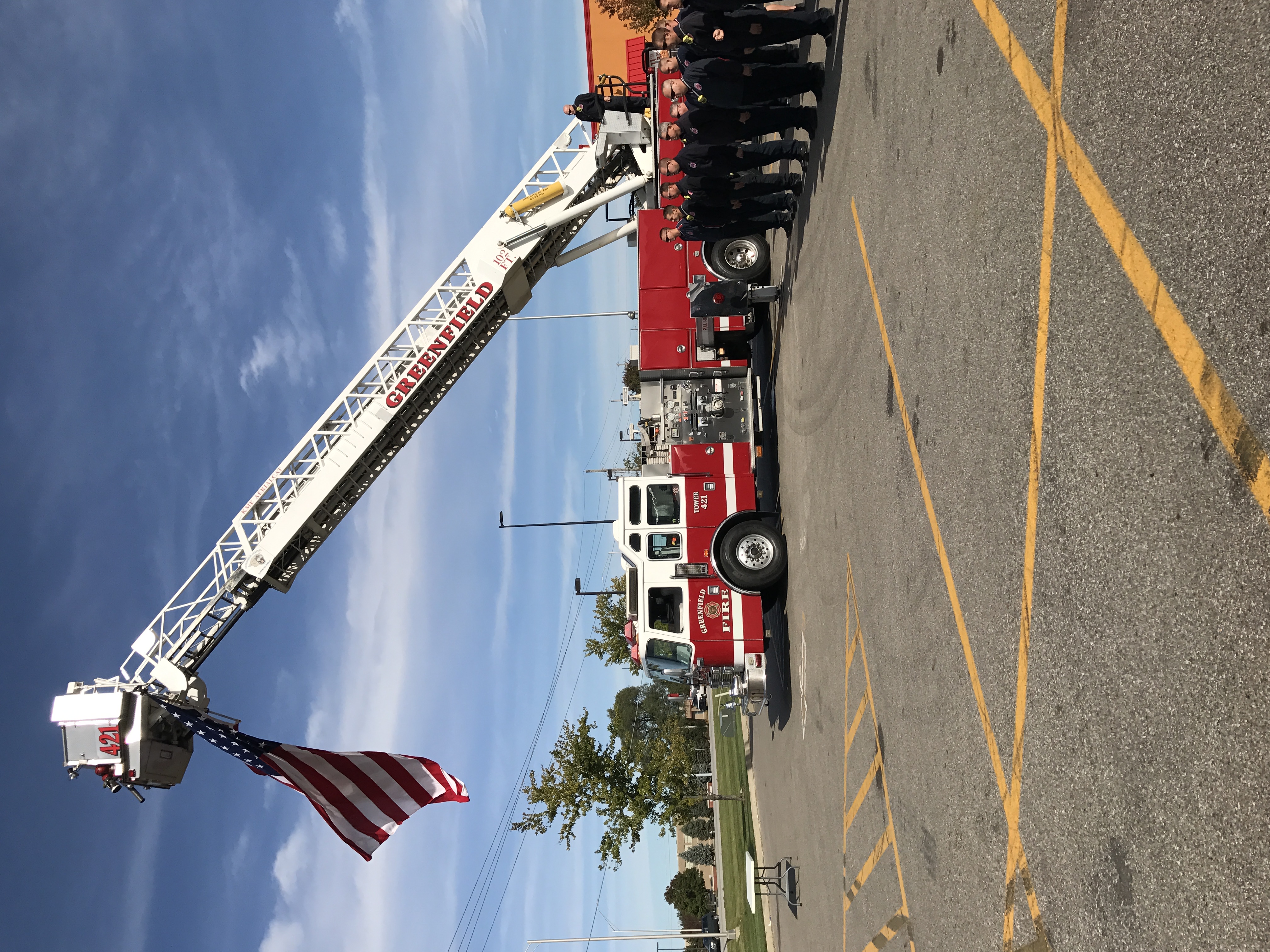 Red firetruck, the arm is lifted, and there’s a flag hanging from the arm of the lift