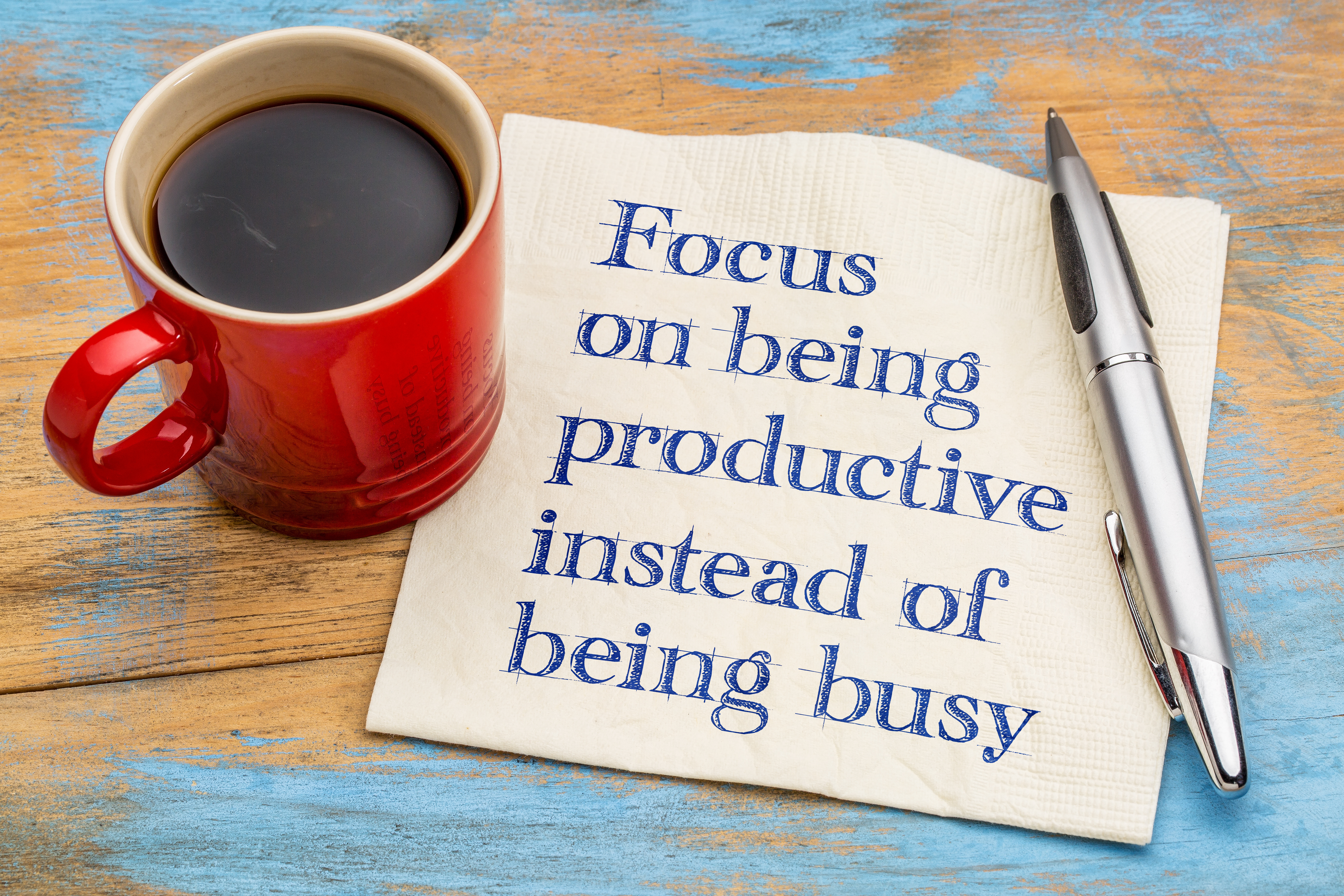 Focus on being productive instead of being busy - handwriting on a napkin with a cup of espresso coffee