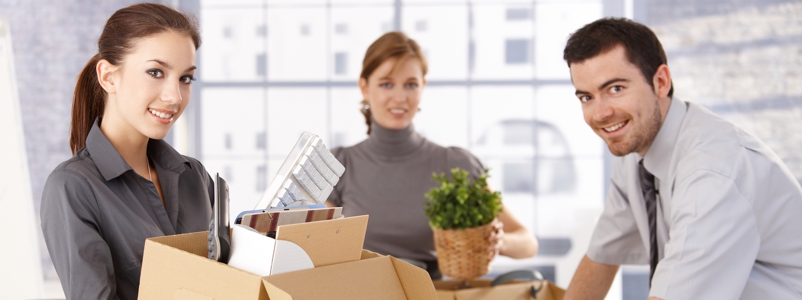 Young office workers moving office, unpacking boxes, smiling.?