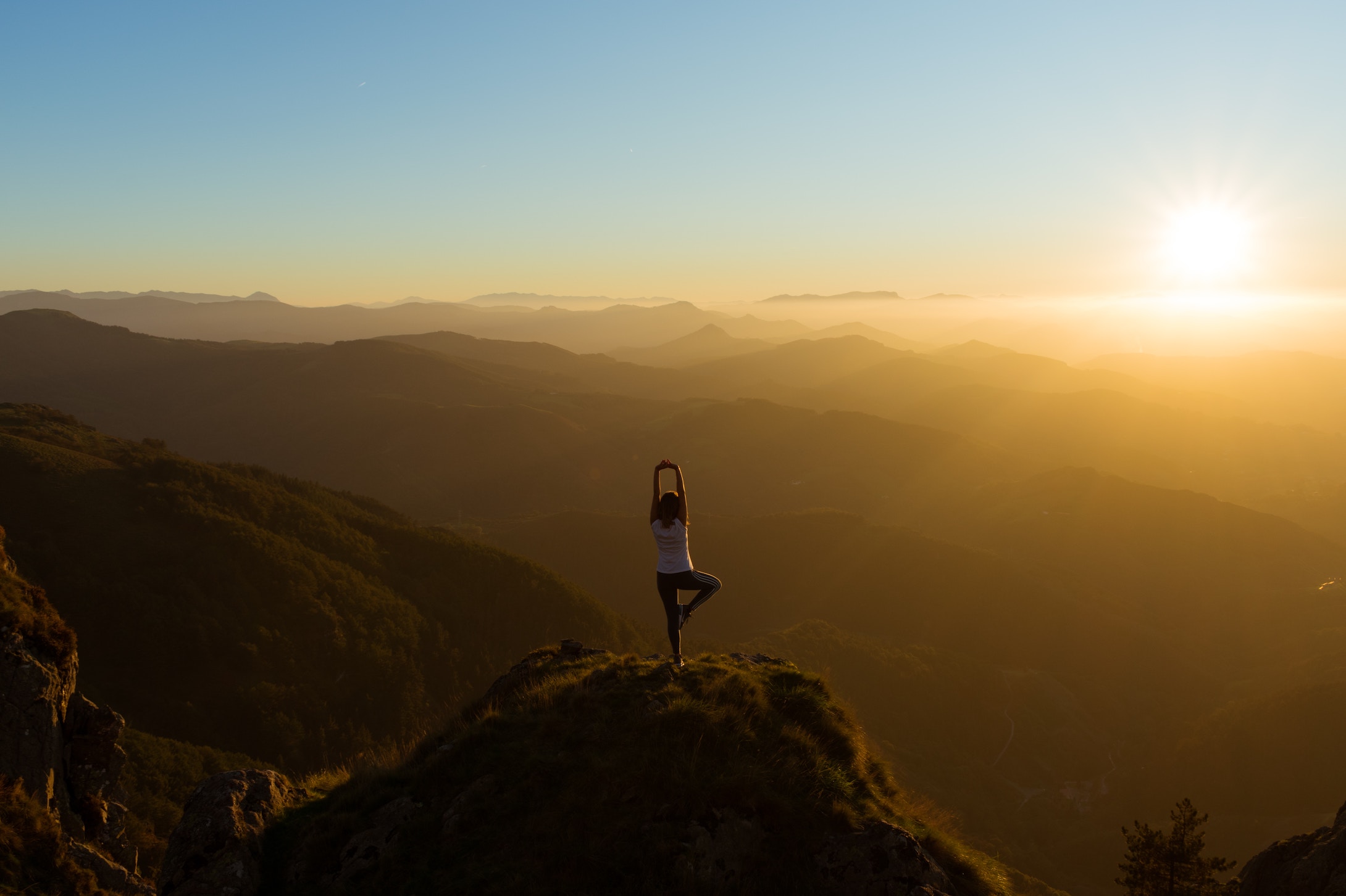 woman stretching on mountain top watching the sunrise