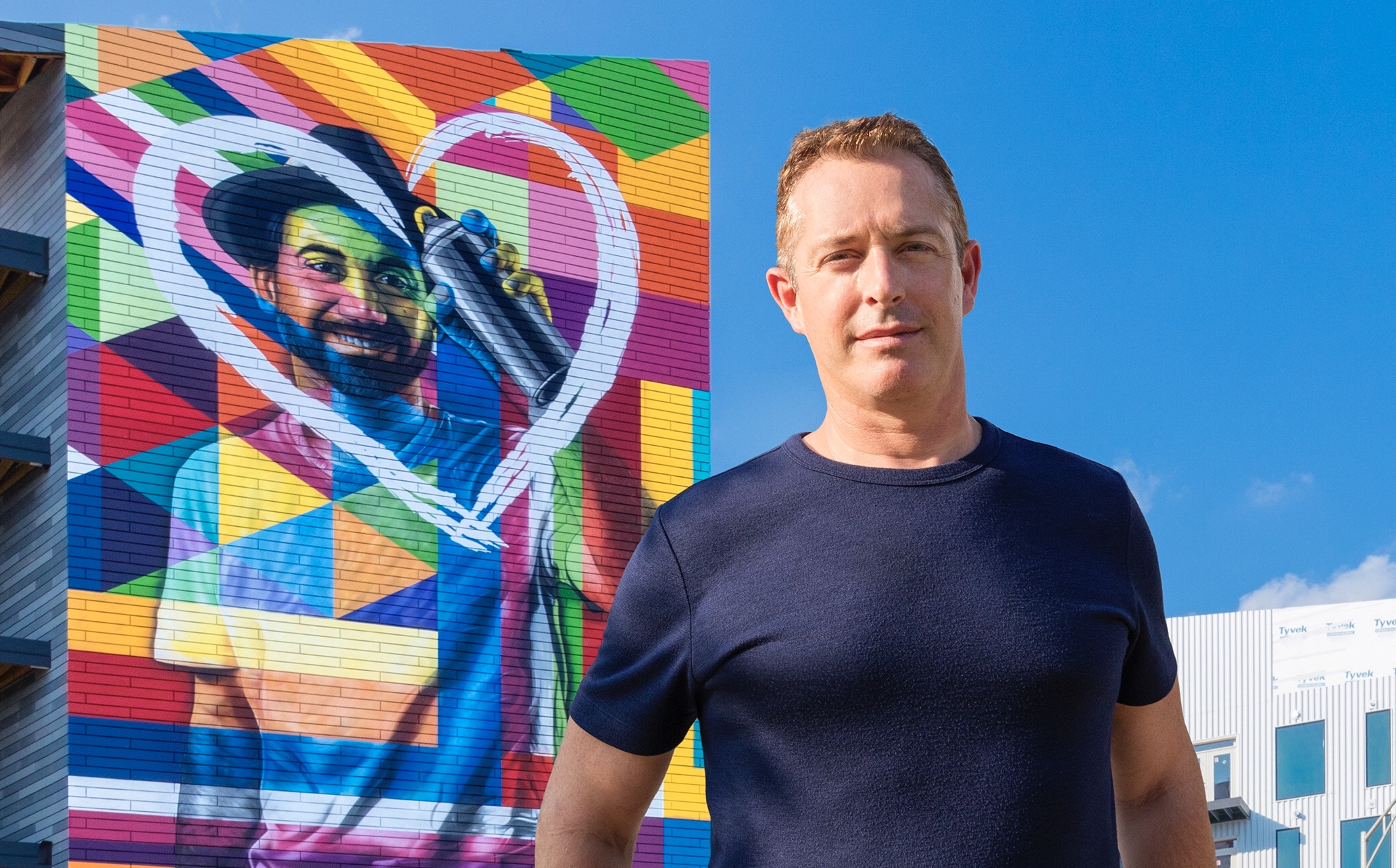 Brett in front of artist Eduardo Kobra&#039;s self-portrait mural at Gravity.