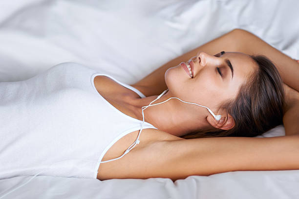 Portrait of a beautiful young woman listening to music while lying on her bed