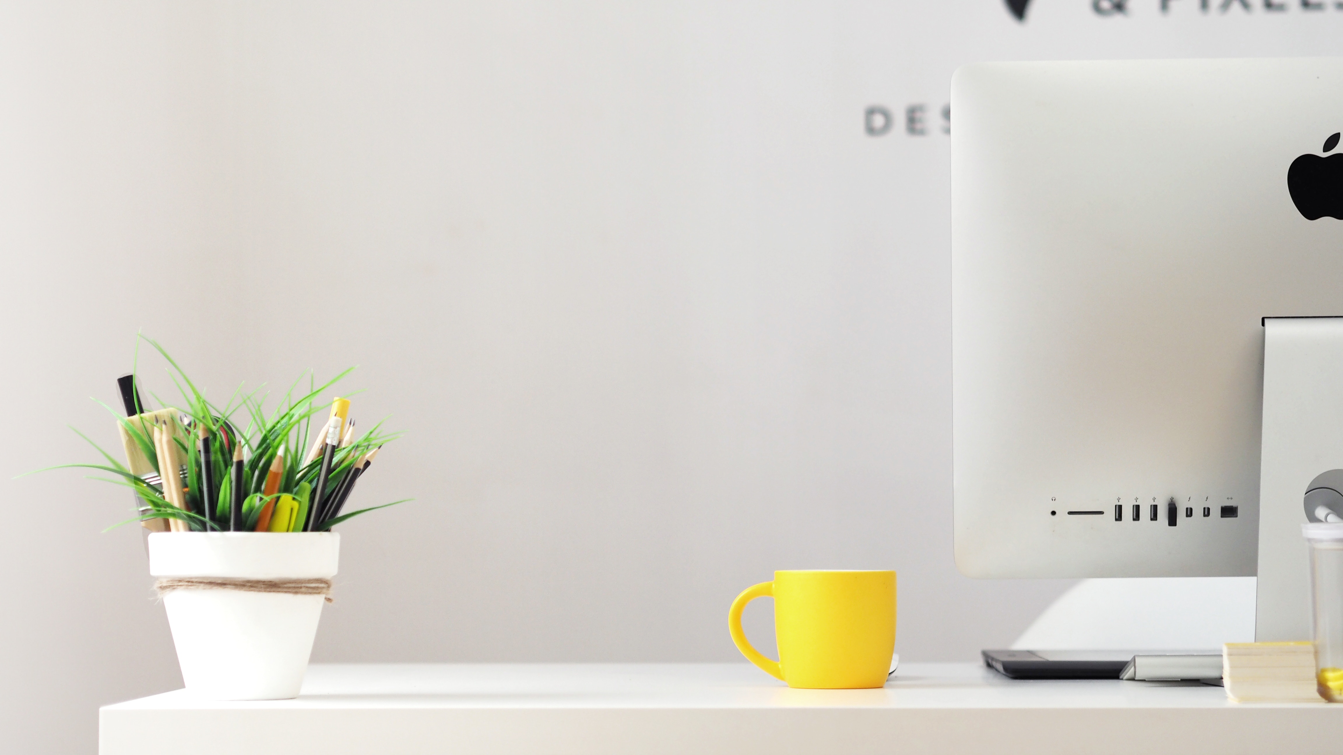 a home office desk with yellow mug and houseplant