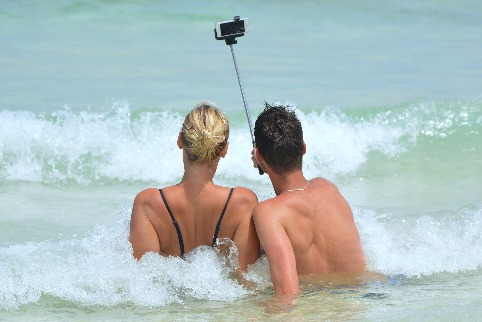 two young people, female and male, taking selfie on the beach