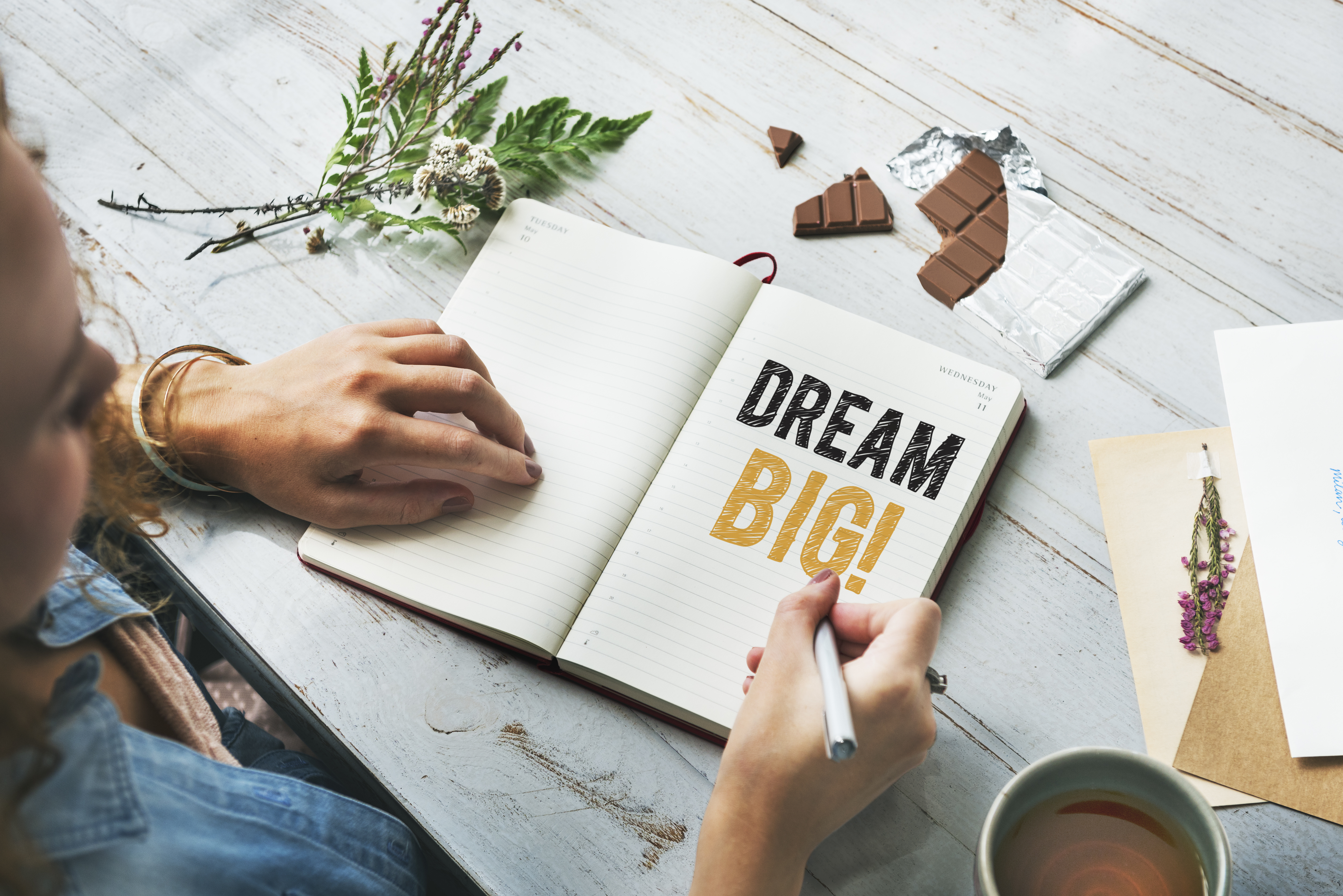 Woman writing Dream big on a notebook