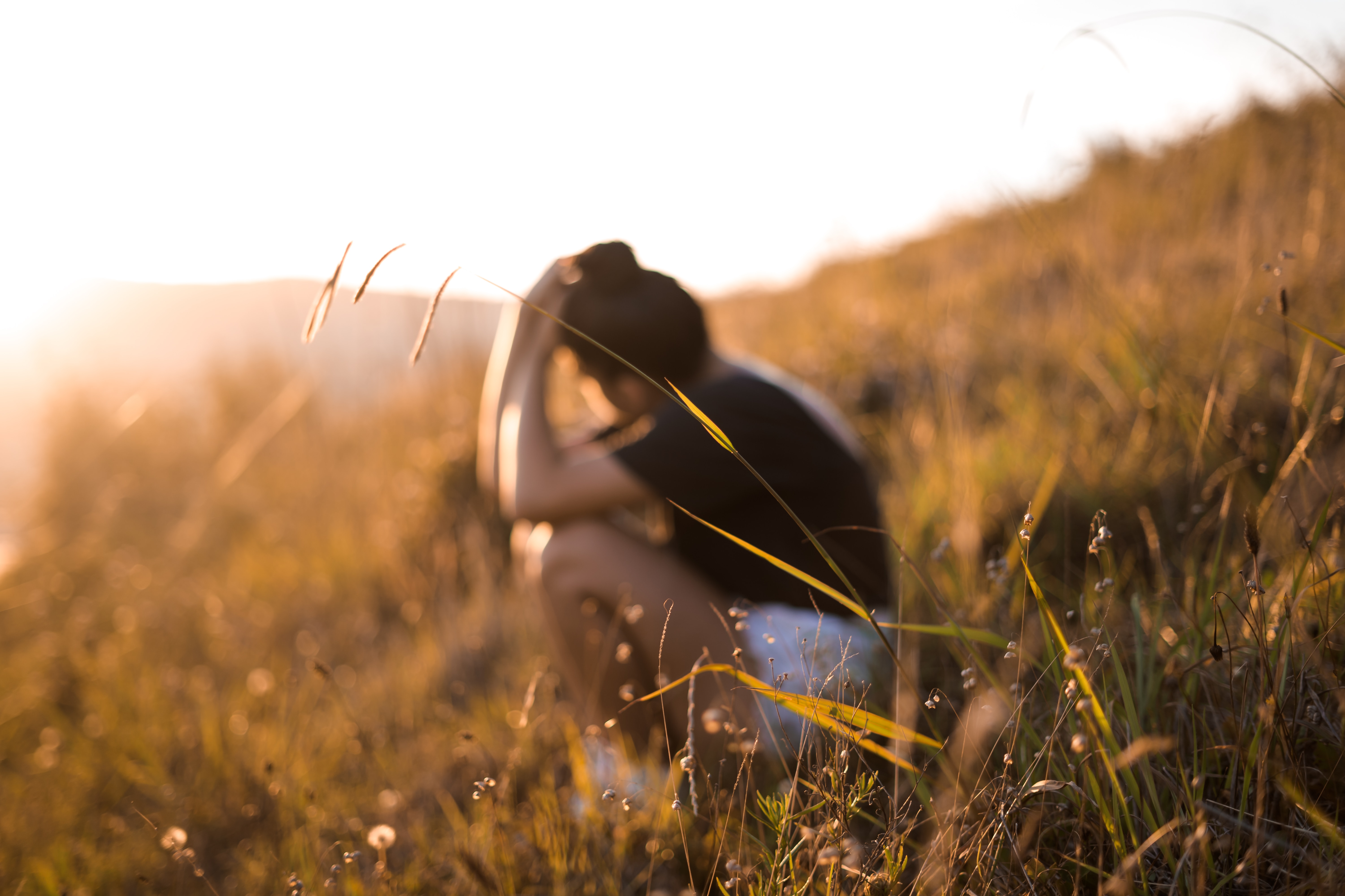 Woman sitting in field pondering over her thoughts