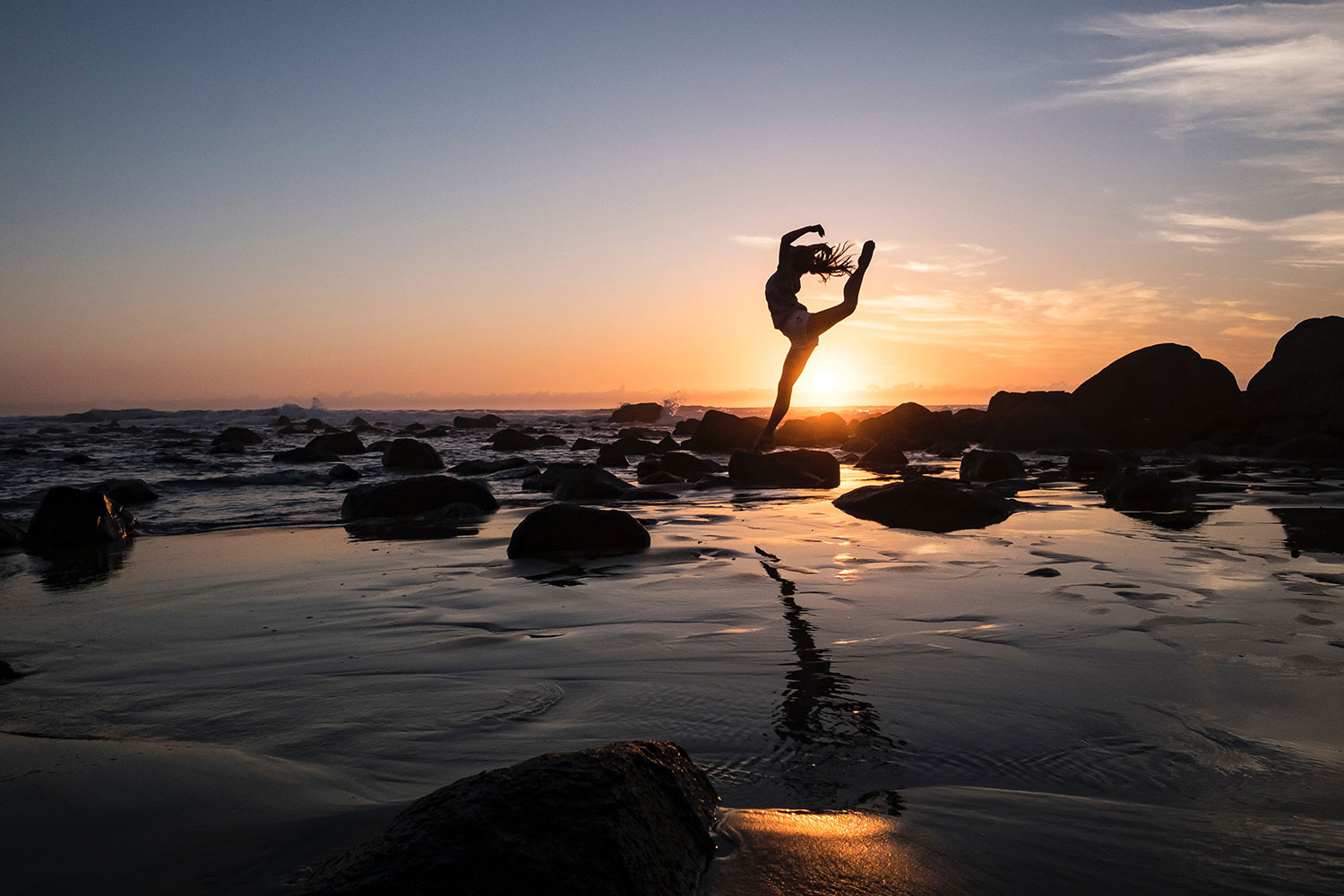 A woman leaping on a beach at sunset