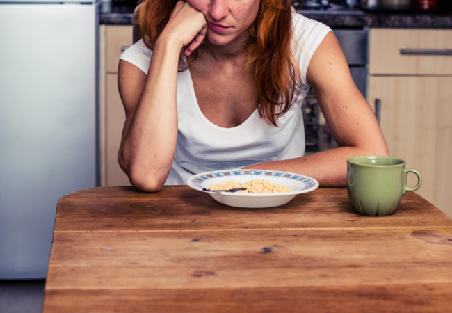 Young woman in her kitchen is dissapointed that she is having cereal for breakfast again