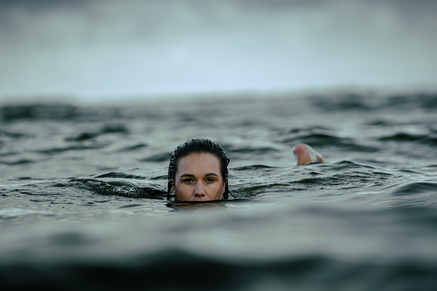 A woman&#039;s face trying to stay afloat in the middle of the ocean