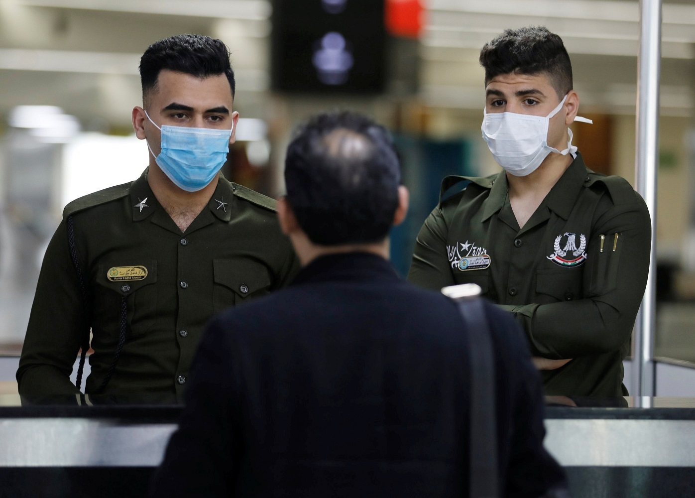 Iraqi police officers wearing protective face masks check a passenger&#039;s passport upon his arrival, following an outbreak of coronavirus, at Baghdad international Airport, in Baghdad, Iraq March 4, 2020. REUTERS/Khalid al-Mousily
