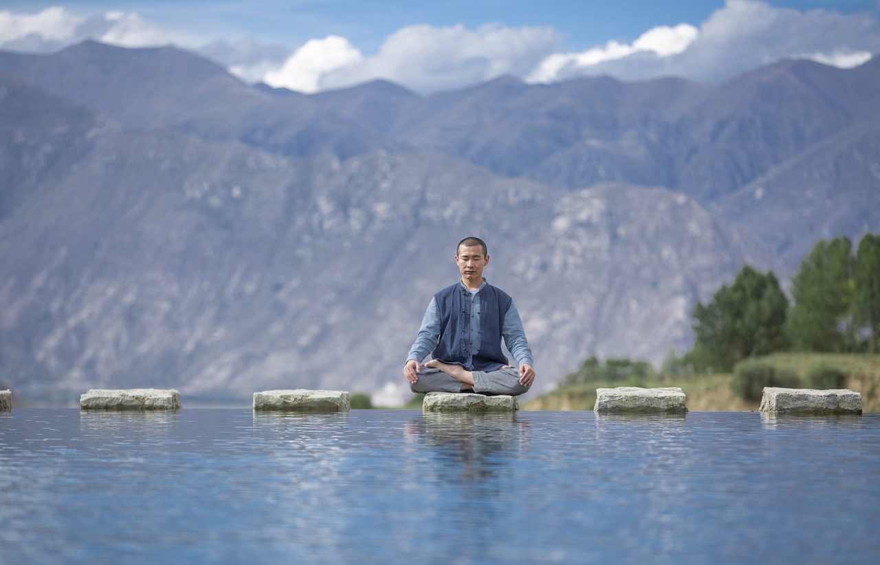 A person meditating on a stepping stone above a body of water