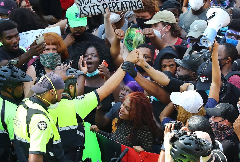 Atlanta Police Officer reaches out in solidarity with protestors outside of CNN Center, Tuesday, June 2, 2020 (Curtis Compton/Atlanta Journal-Constitution via AP)