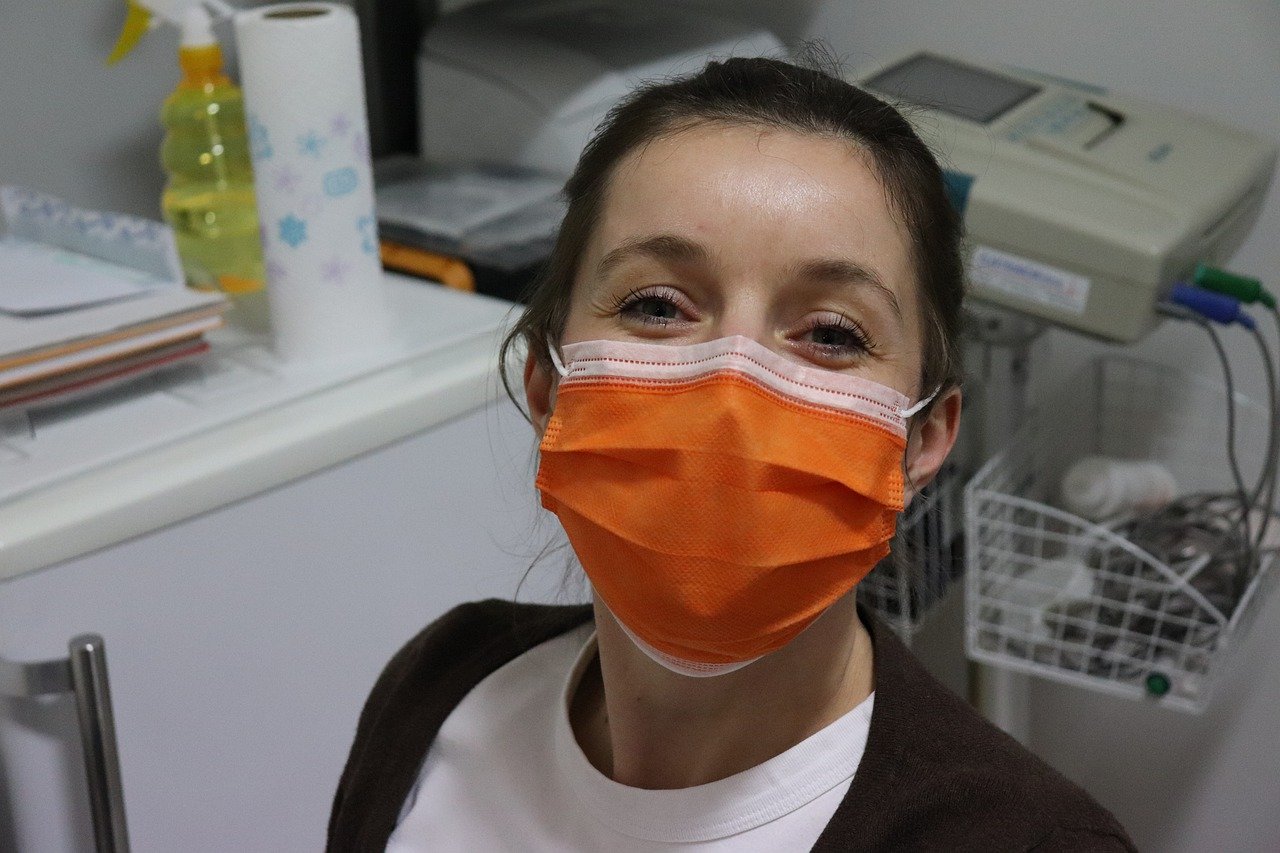 A female healthcare worker wearing a smile under an orange surgical mask