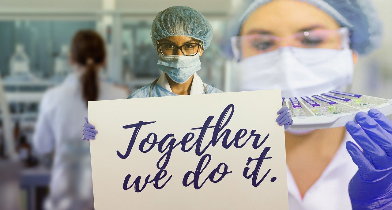 A femal healthcare professional holding a banner that reads &quot;Together we do it.&quot;