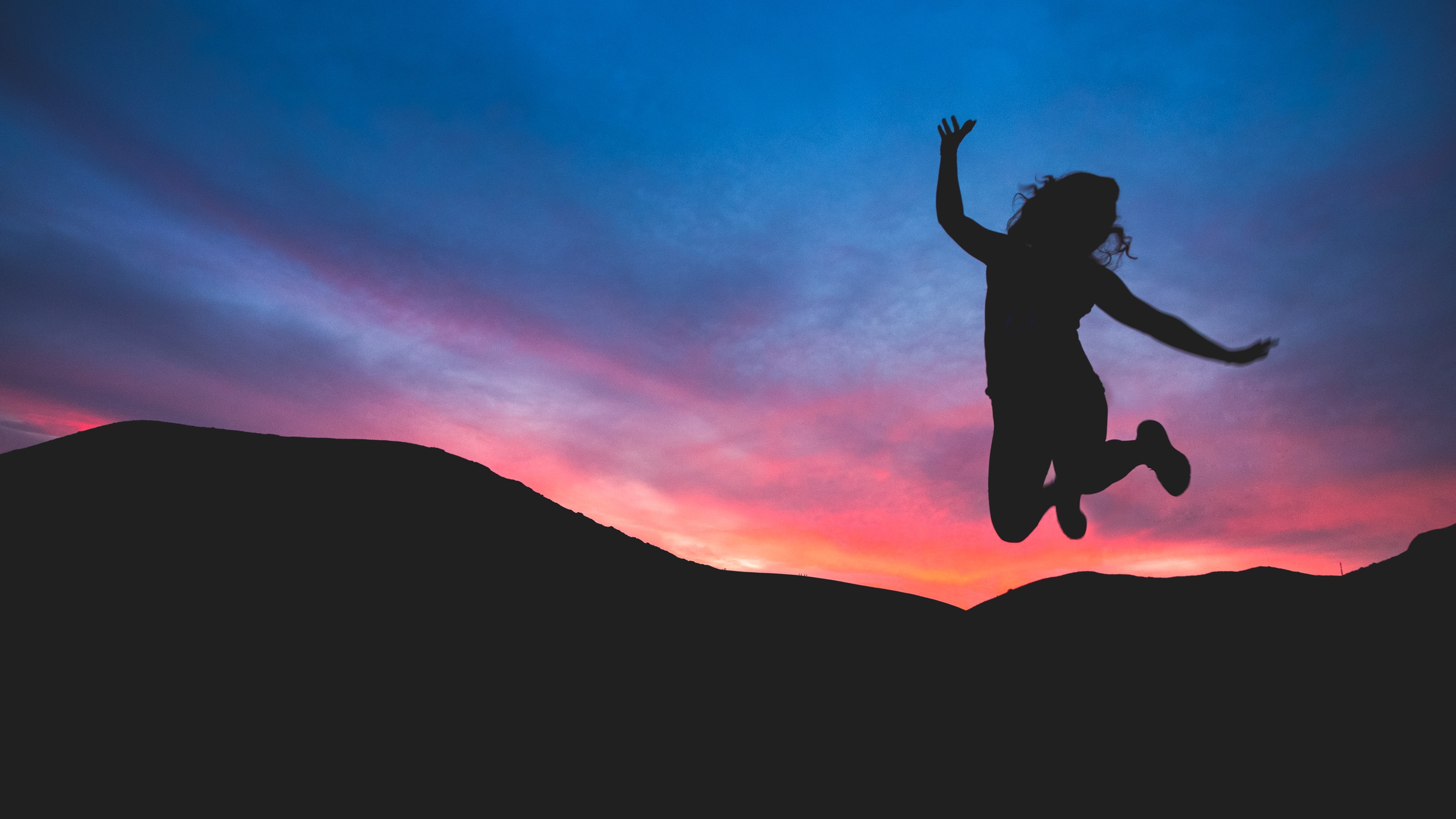 Happy woman jumping by a sunset