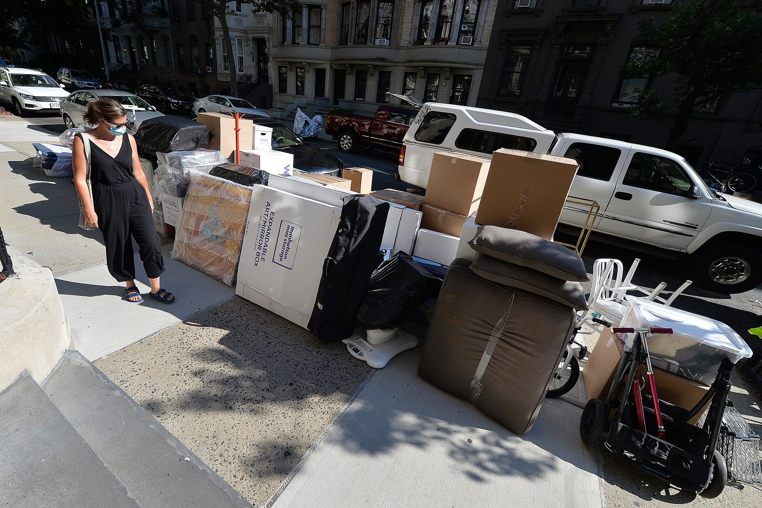 A woman wearing a mask in the time of COVID-19, walks past Moving boxes stacked in front of an Upper West Side brownstone, waiting for movers to finish packing the belongings of former tenants that have already relocated out of state, New York, NY, July 13, 2020. Complicated by the economic impact of the COVID-19 pandemic, months of shelter in place, daily protests, social clashes and and the slow reopening of the economy, have forced many New Yorkers to leave a city where rents are high and future job opportunities are difficult to predict. (Anthony Behar/Sipa USA)No Use UK. No Use Germany.