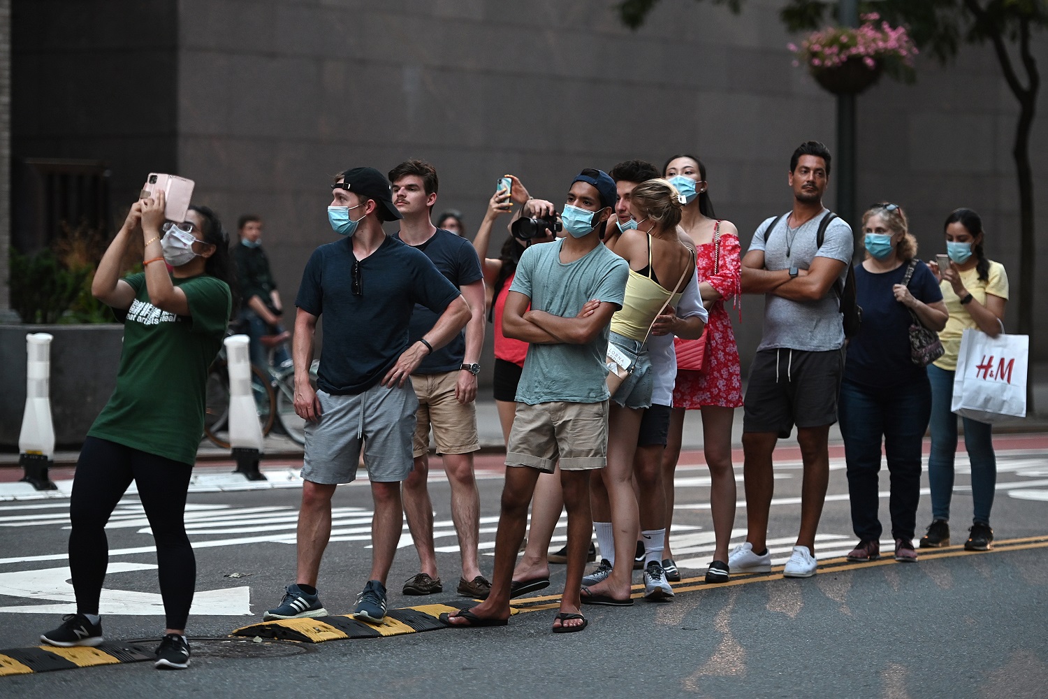 Some wearing face masks in the time of COVID-19, people line up along the median strip along 42nd Street and Second Avenue waiting for the sunset phenomenon known as Manhattanhenge, which was not viewable from that location for a second night in a row due to lingering storm clouds on the horizon, New York, NY, July 12, 2020. Manhattanhenge is the event during which the setting (or rising) sun aligns perfectly with east-west streets of the Manhattan island street grid, which occurs twice a year. (Anthony Behar/Sipa USA)No Use UK. No Use Germany.