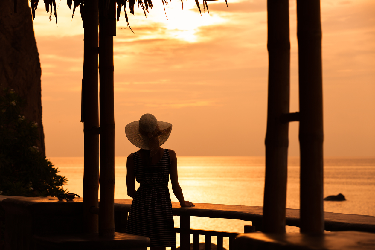 Woman enjoying beautiful sunset from the hotel balcony. Travel concept.
