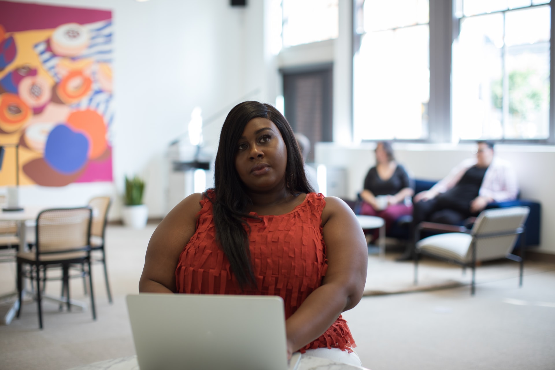 10 Ways Freelance Writers can Fight Imposter Syndrome Featured image: young black woman sitting in front of a laptop pondering something.