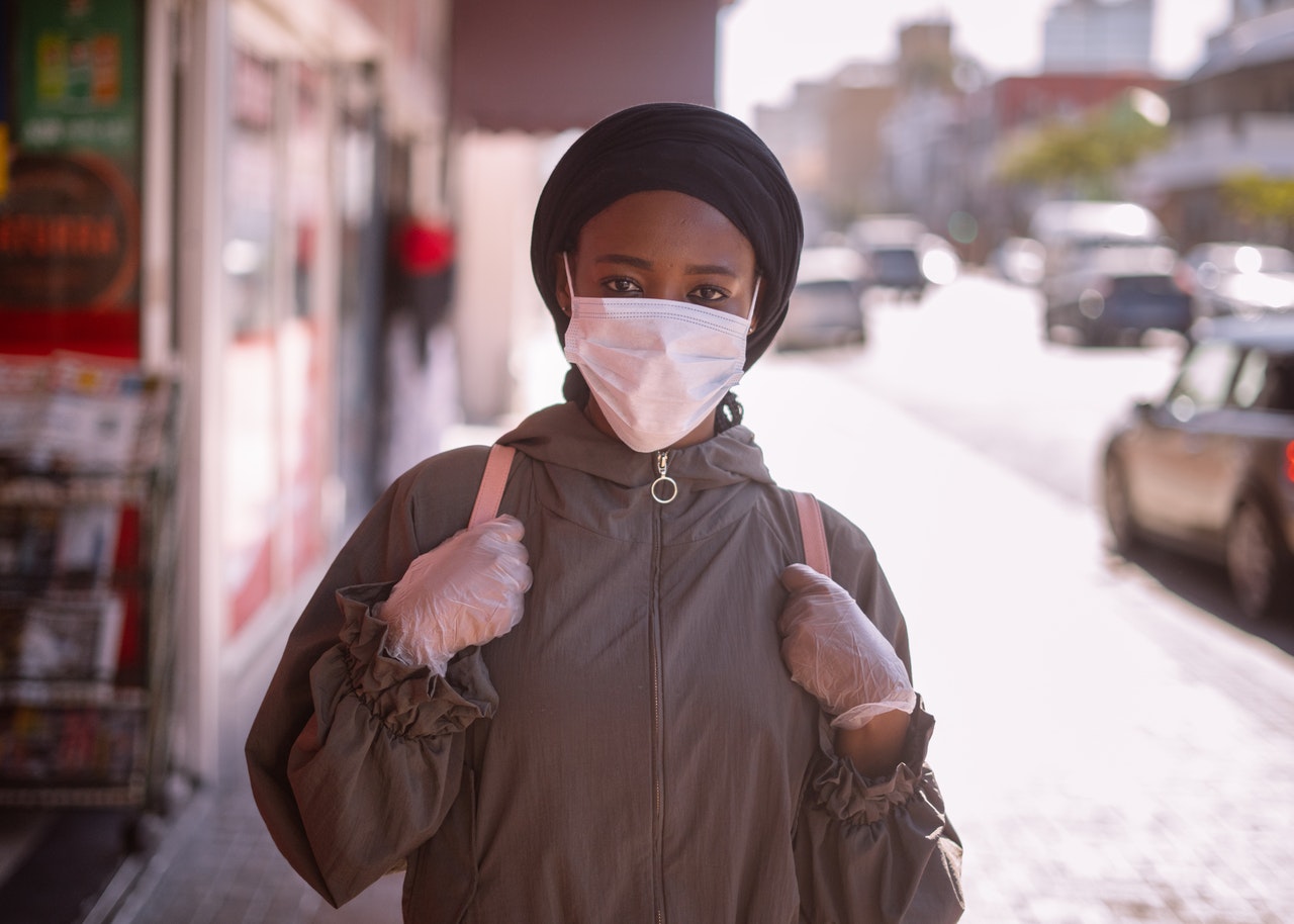 A black American woman walking with mask and gloves on
