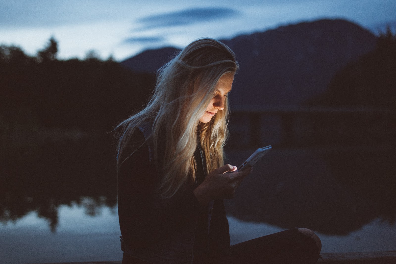 girl staring at phone outside at dusk