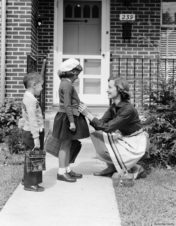 UNITED STATES - CIRCA 1950s:  Mother outside front door, buttoning sweater of daughter going off to school with her brother. (Photo by H. Armstrong Roberts/Retrofile/Getty Images)