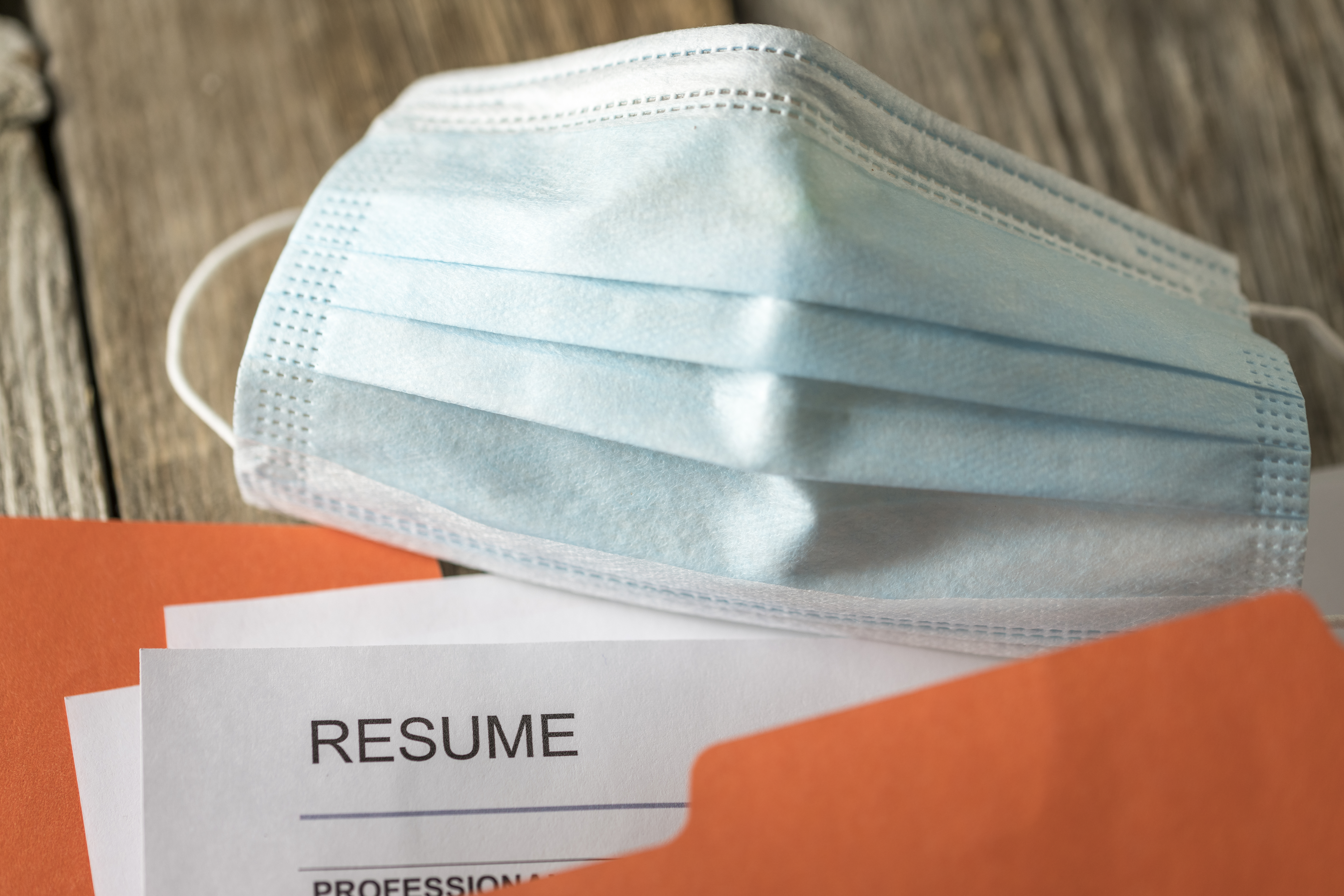 Stock photograph of job resume inside orange folder with mask.