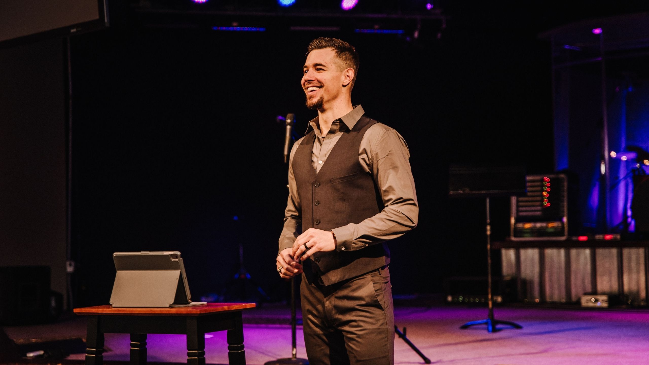 Man in a suit standing on a stage smiling