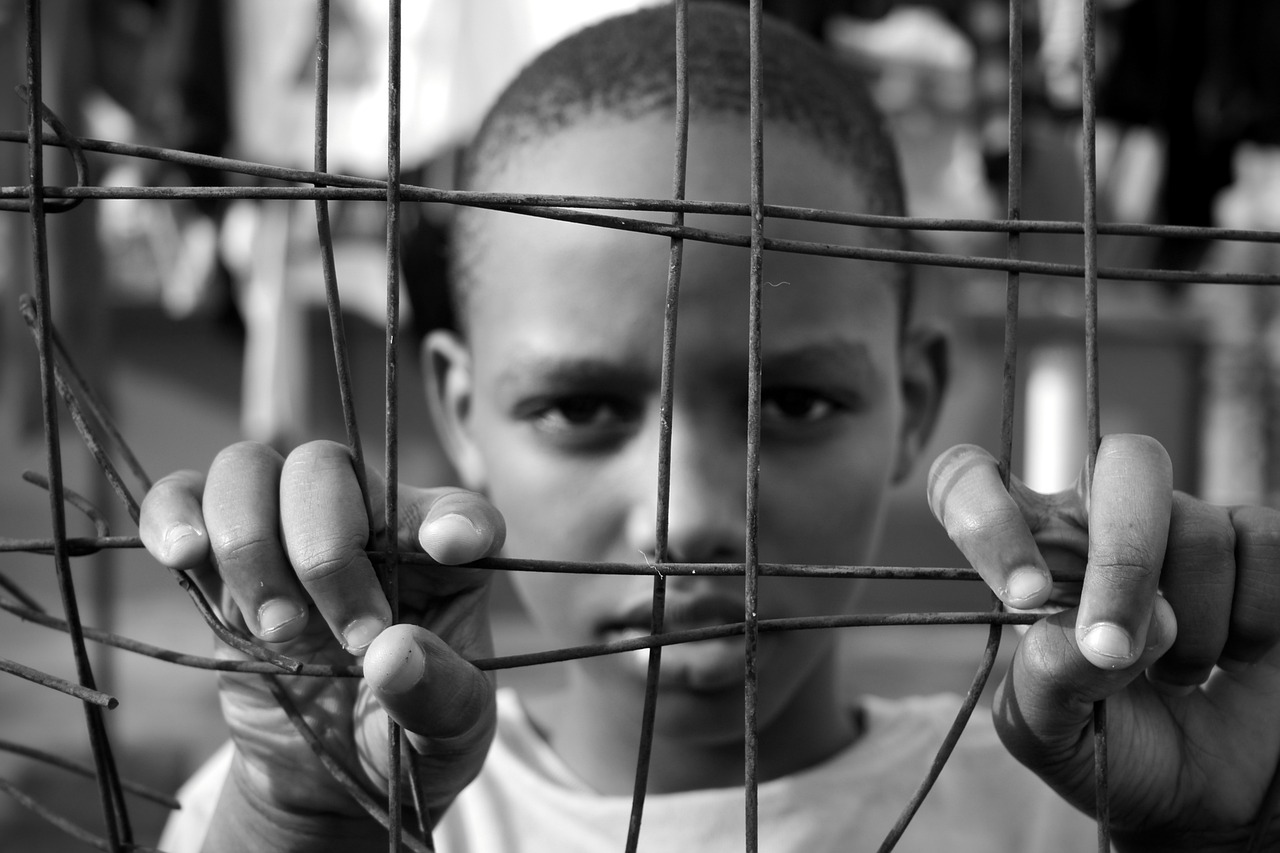 An African American teenager behind wire fencing