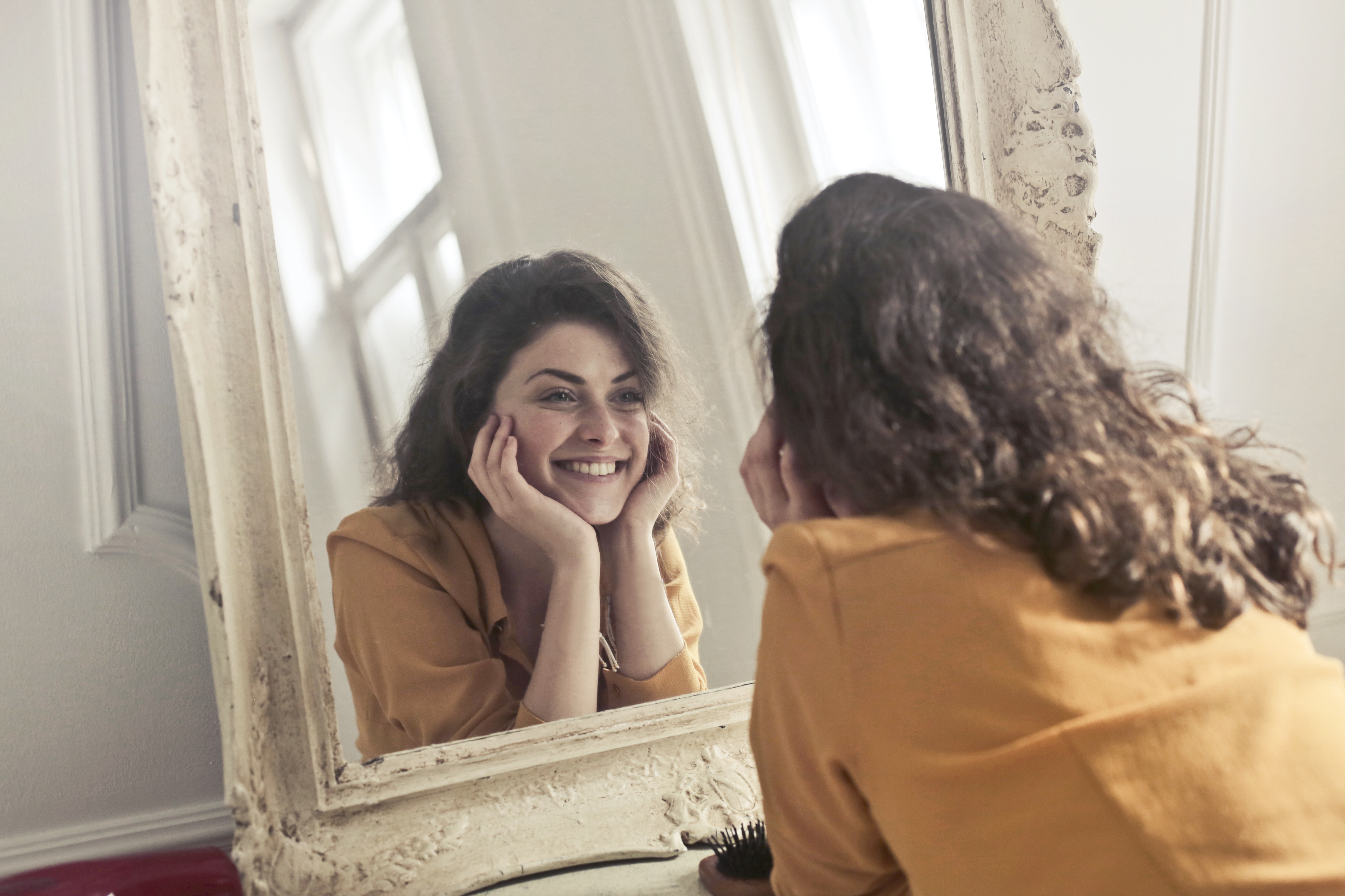 Woman looking at her smiling image on the mirror