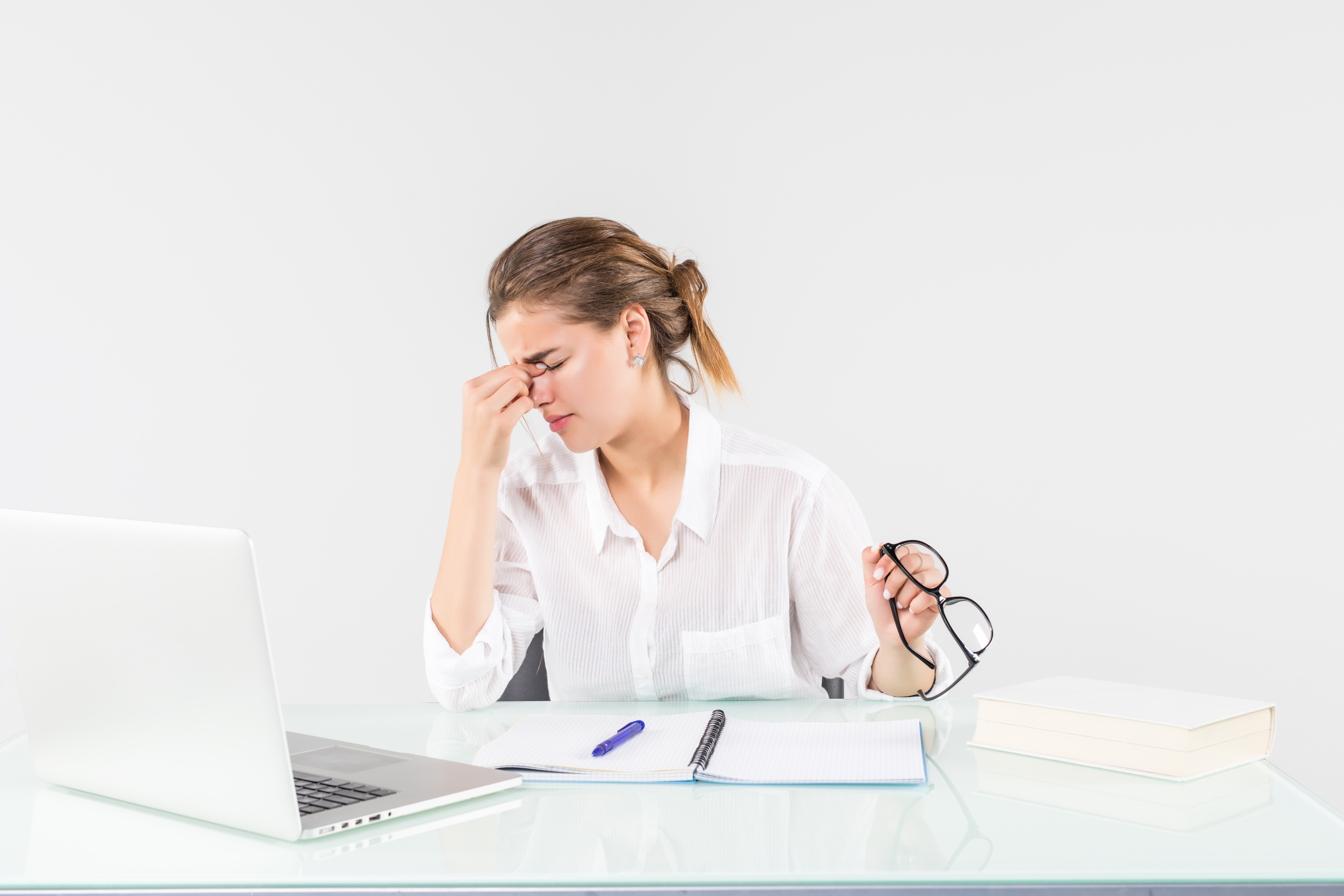 A tired woman in front of a laptop, isolated on white background