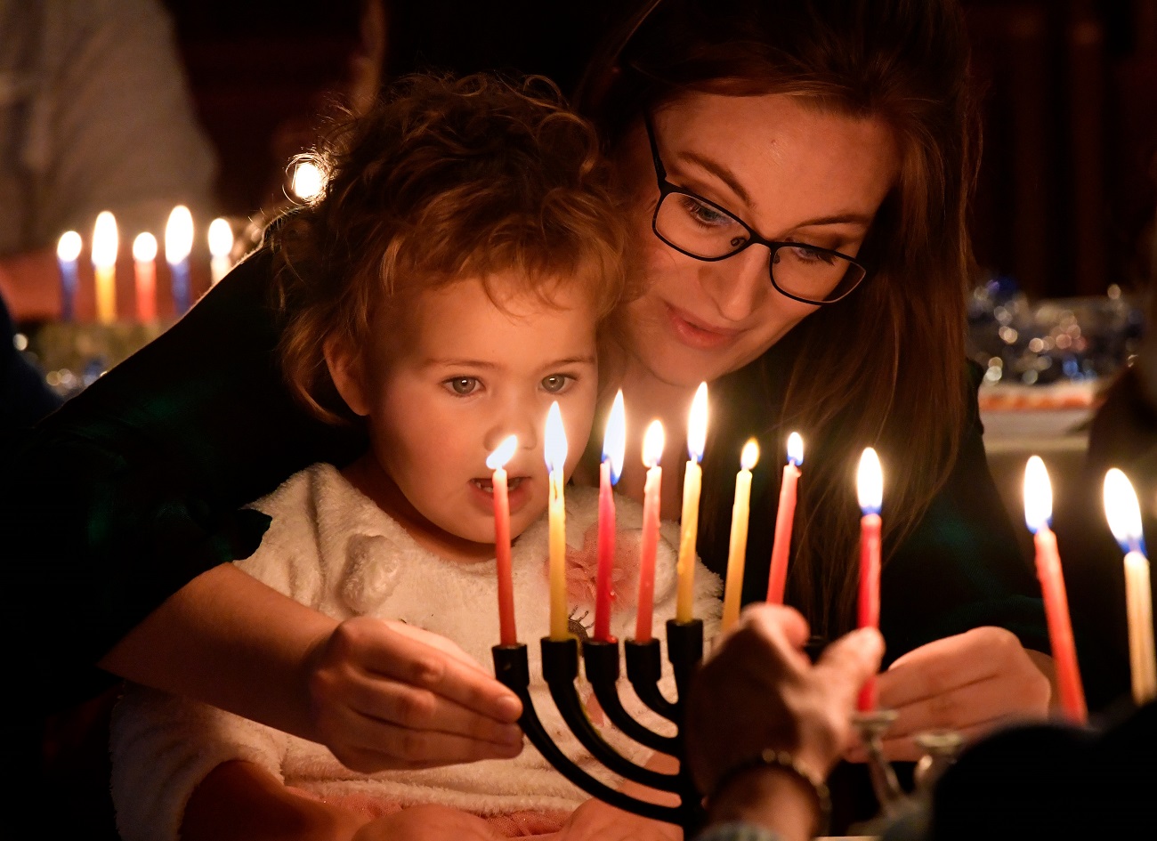 Leslie Moulard lights a menorah with her two-year-old daughter Moira during Hanukkah festivities at Temple Mizpah Friday Dec. 27, 2019.1231hanukkah2