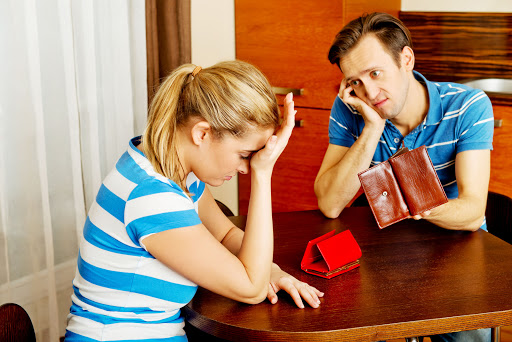 59093903 - worried couple sitting at the table with empty wallets.