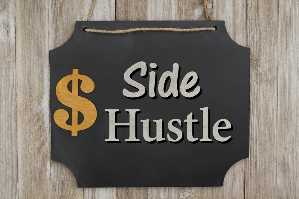 Making money with your side hustle, Hanging chalkboard with a dollar sign on weathered wood wall with text Side Hustle