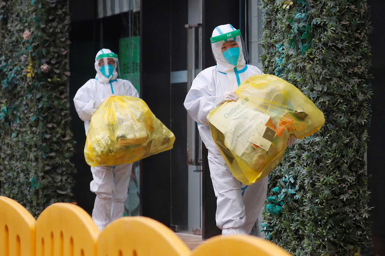 People in protective suits walk outside the hotel where members of the World Health Organisation (WHO) team tasked with investigating the origins of the coronavirus (COVID-19) pandemic are quarantined, in Wuhan, Hubei province, China January 28, 2021. REUTERS/Thomas Peter