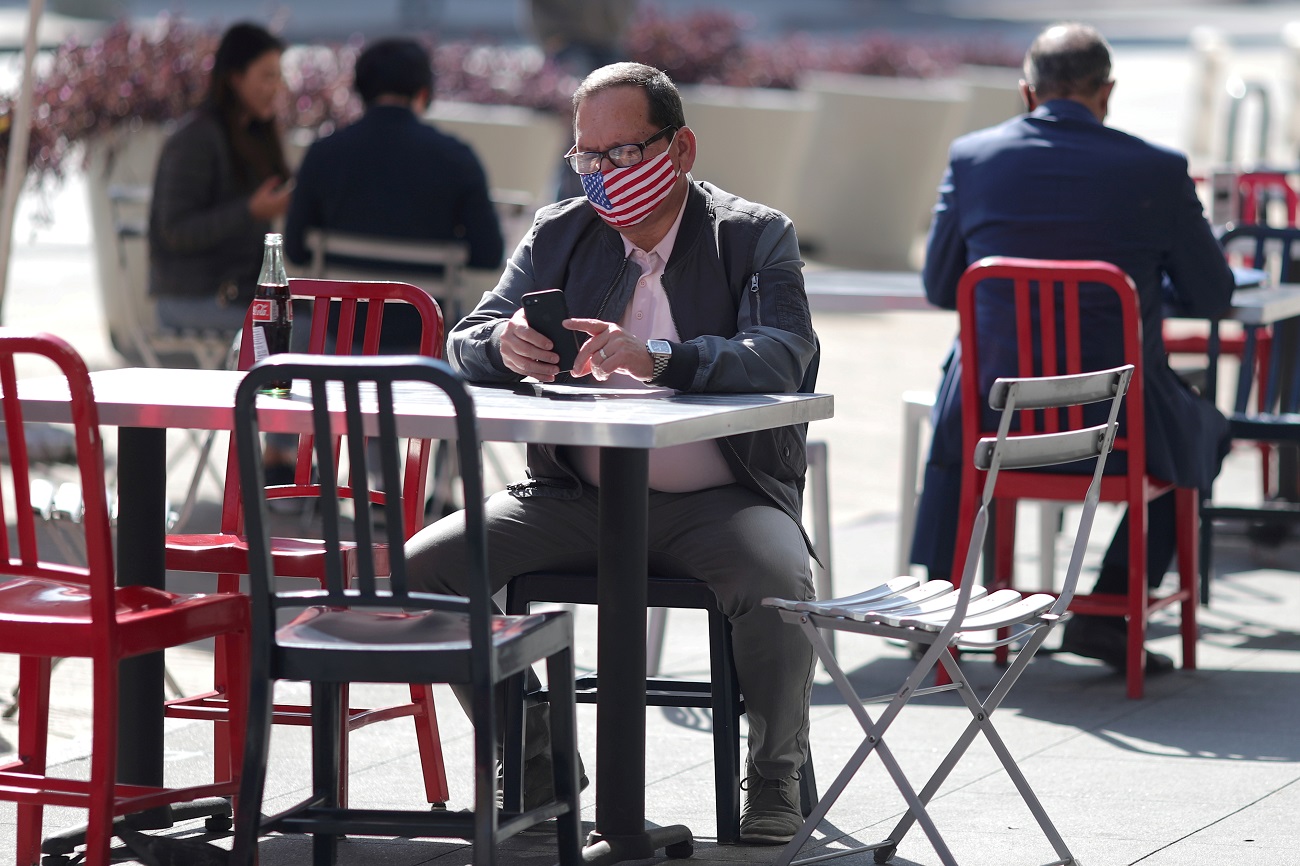 FILE PHOTO: A man sits at an outdoor dining table at Grand Central Market, as the coronavirus disease (COVID-19) outbreak continues, in Los Angeles, California, U.S., February 3, 2021. REUTERS/Lucy Nicholson/File Photo