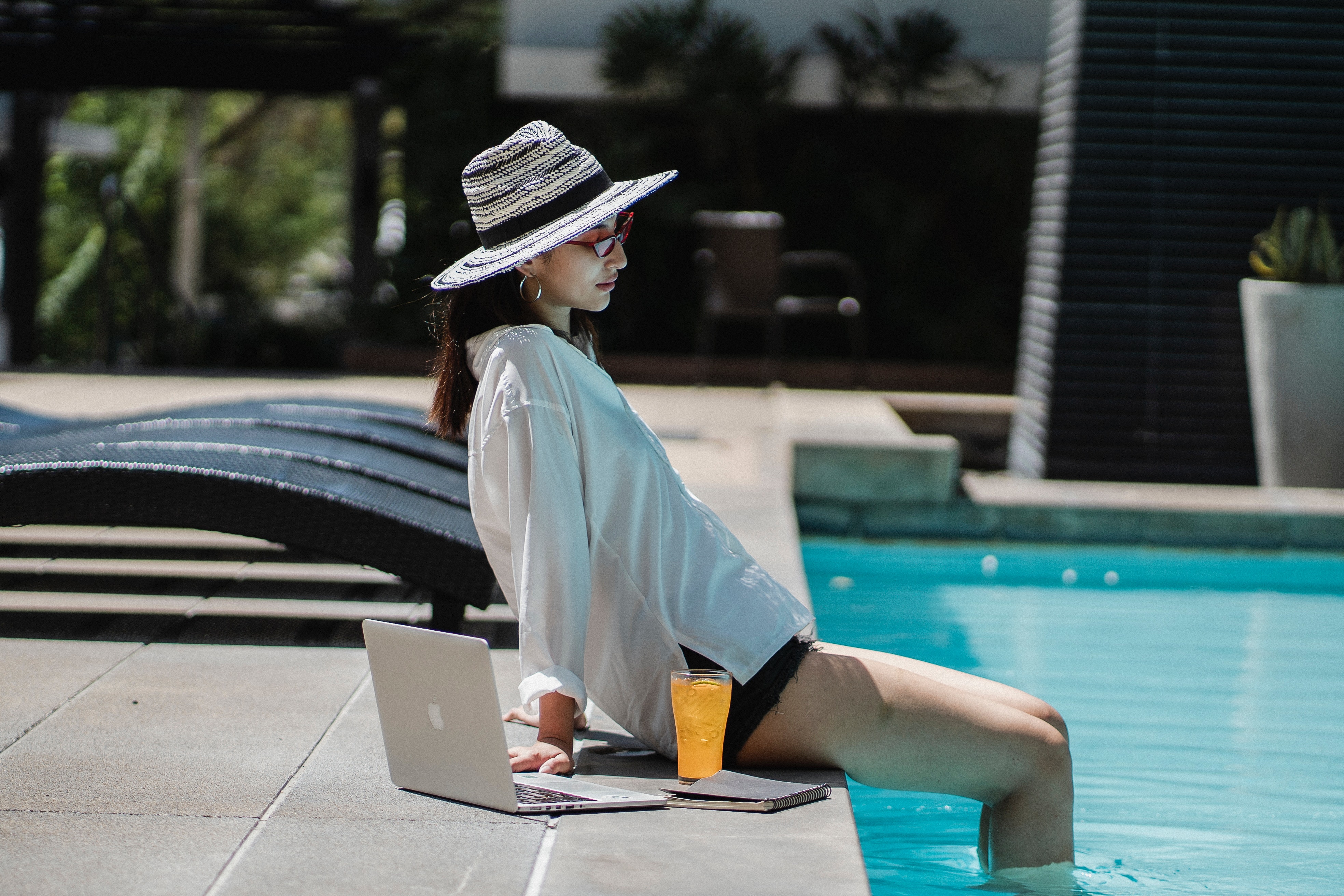 Woman relaxing by pool with laptop
