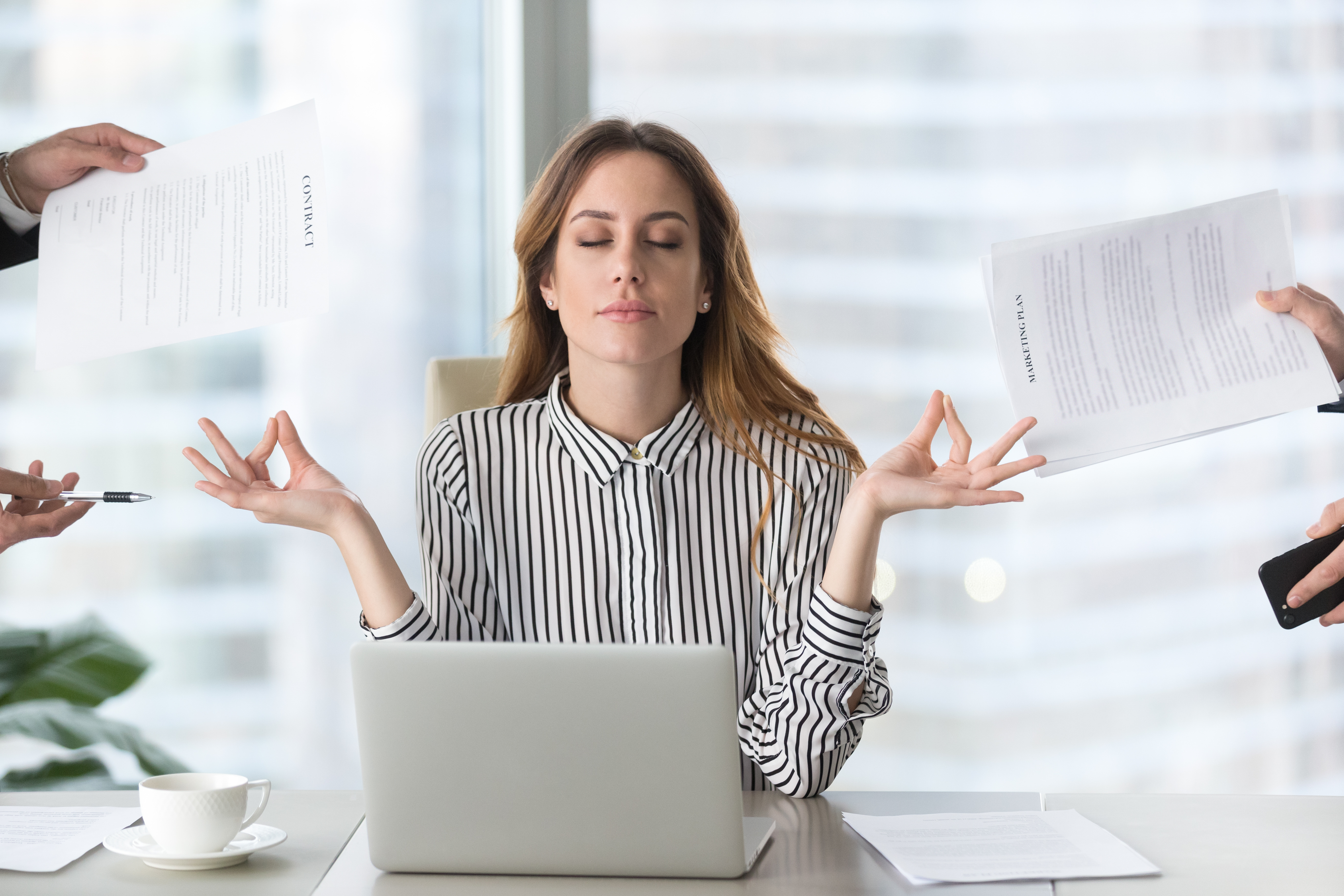 Calm female executive meditating taking break at work for mental balance, mindful businesswoman feeling relief and no stress doing yoga at work ignoring avoiding stressful job and paperwork in office