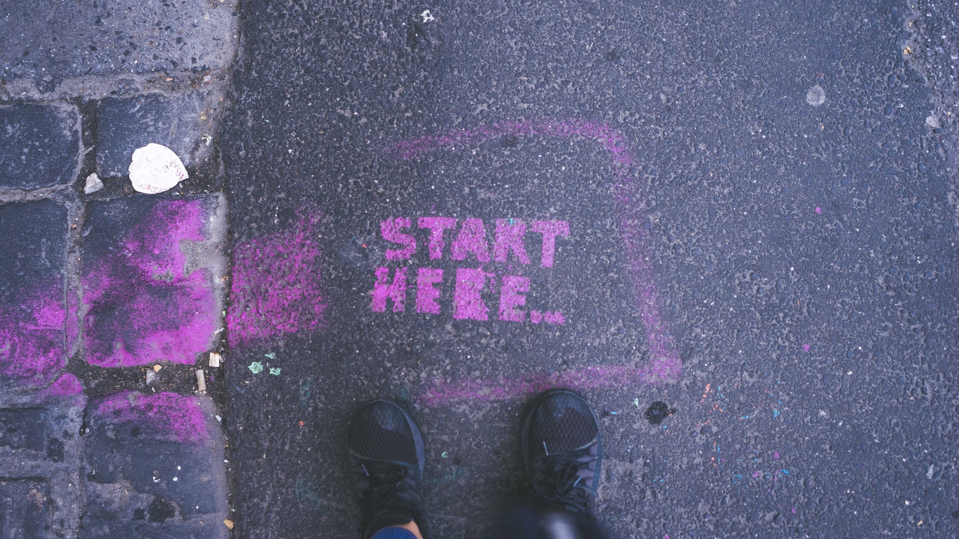 &quot;Start Here&quot; in purple paint on the pavement