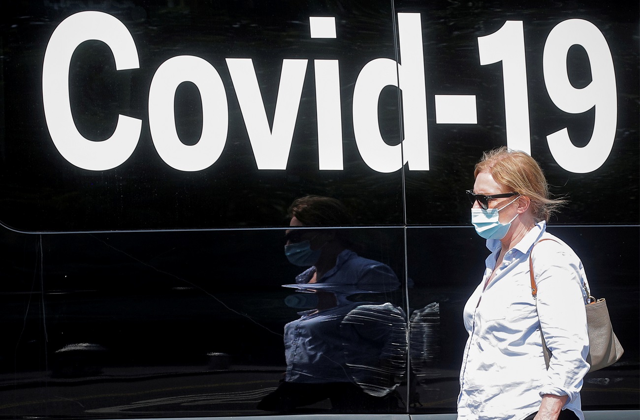 FILE PHOTO: A woman wearing a mask passes by a coronavirus disease mobile testing van, as cases of the infectious Delta variant of COVID-19 continue to rise, in Washington Square Park in New York City, U.S., July 22, 2021.  REUTERS/Brendan McDermid/File Photo