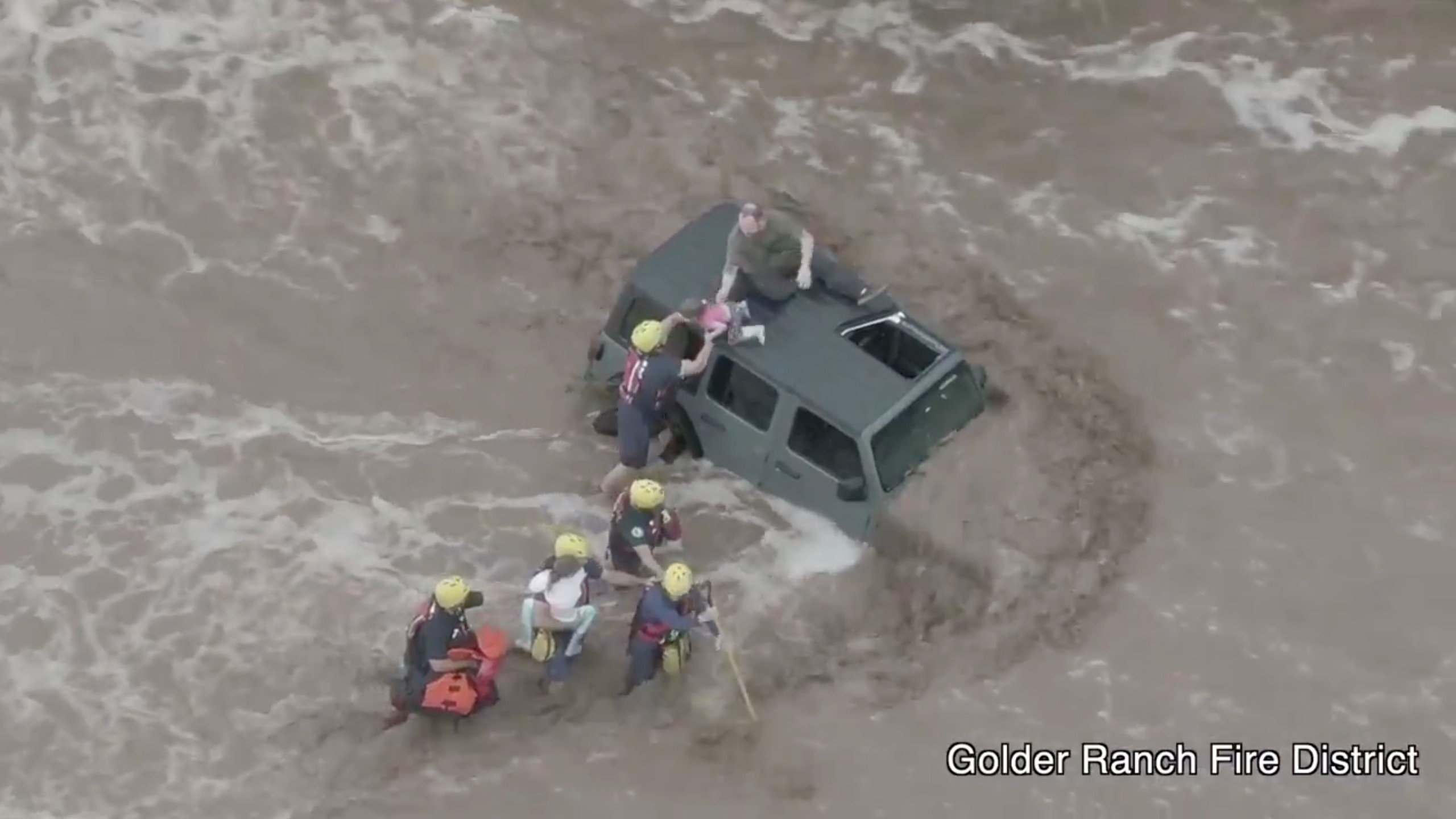 Firefighters rescue a man and two young girls who were stranded after their vehicle was washed away in flash floods near Tucson, Arizona, U.S., July 14, 2021, in this still image taken from video footage obtained from social media. Golder Ranch Fire District/via REUTERS THIS IMAGE HAS BEEN SUPPLIED BY A THIRD PARTY. MANDATORY CREDIT. NO RESALES. NO ARCHIVES. MUST NOT OBSCURE LOGO.