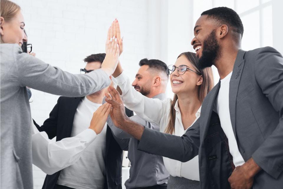 business men and women high fiving in a group