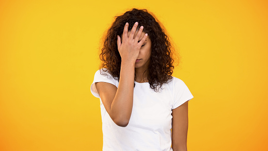 Discontent biracial lady gesturing face palm on camera against yellow background